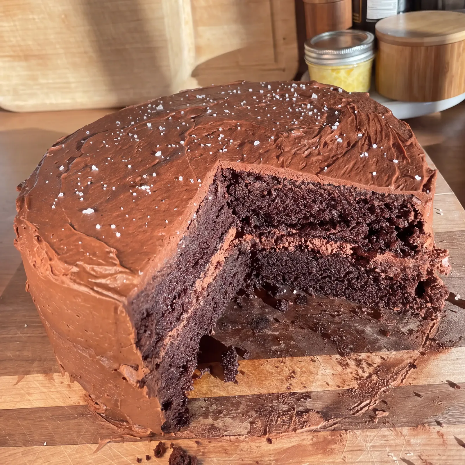 Chocolate layer cake with fudgy frosting and flaky salt, a slice cut away