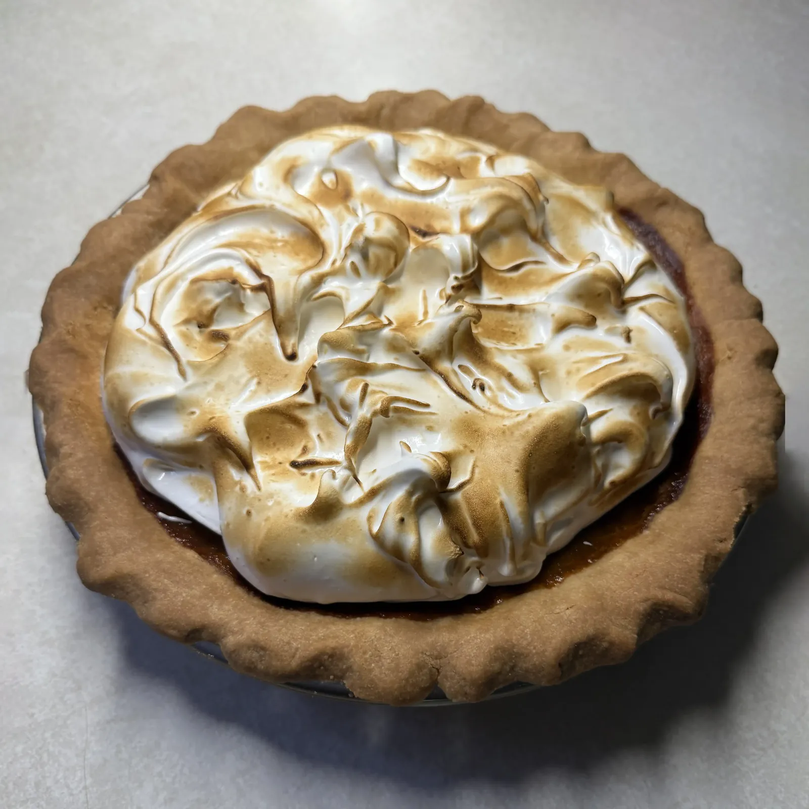 Pie topped with swirls of toasted meringue in a golden crimped crust